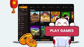 A white beckoning cat (maneki-neko) holding a "PLAY GAMES" sign in front of a laptop.