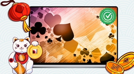 A Maneki-neko cat and gold coins in front of a laptop displaying card suits.