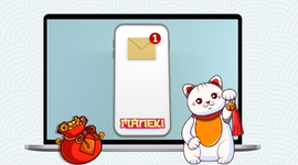 A lucky cat next to a laptop displaying a mobile phone with a notification and a bag of coins.