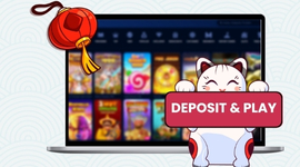 A lucky cat holding a "Deposit & Play" sign in front of a laptop showing various casino games.